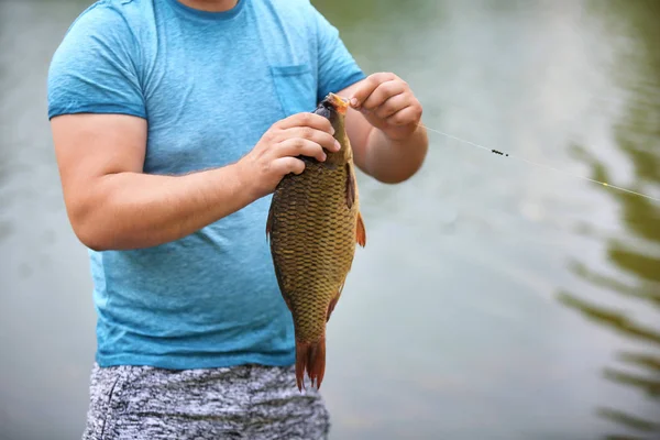 川の土手で獲れたて魚を持つ男 — ストック写真