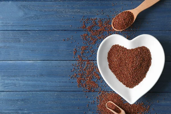 Plate in shape of heart with quinoa seeds on wooden table — Stock Photo, Image