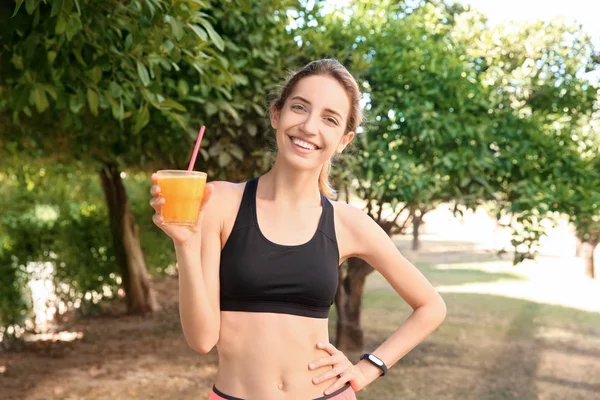 Joven hermosa mujer bebiendo jugo después de correr, al aire libre —  Fotos de Stock