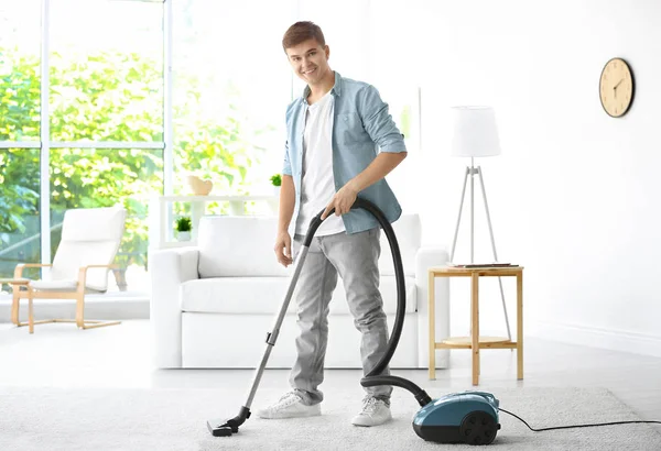 Man rengöring vit matta med vakuum i vardagsrum — Stockfoto