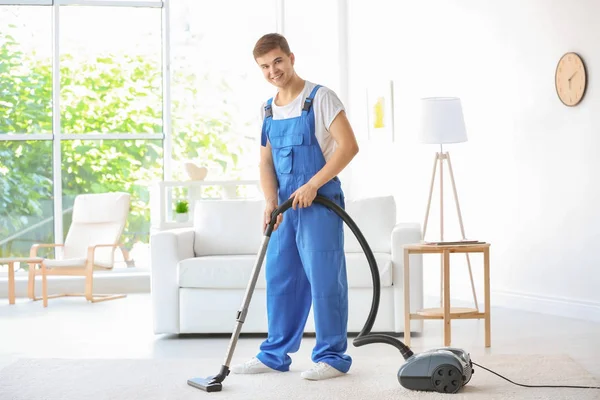 Mann reinigt weißen Teppich mit Staubsauger im Wohnzimmer — Stockfoto