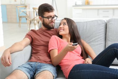 Evde televizyon izleyen genç bir çift.