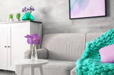 Modern iç leylak aksanıyla. Çiçekler ve rahat kanepe oturma odasında içeren tablo