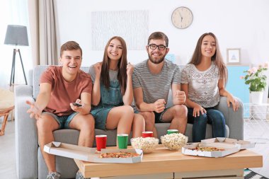 Arkadaşlar evde televizyon izliyor.