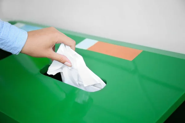 Woman throwing paper into litter bin outdoors