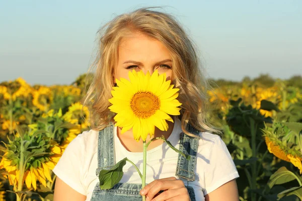Junge Frau posiert mit Sonnenblume im Feld — Stockfoto