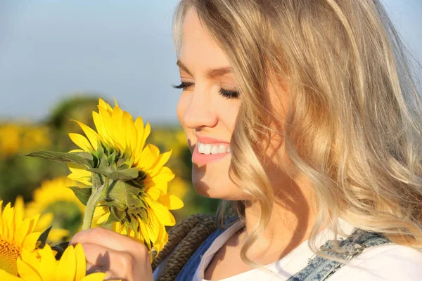 Mujer joven oliendo girasol en el campo —  Fotos de Stock