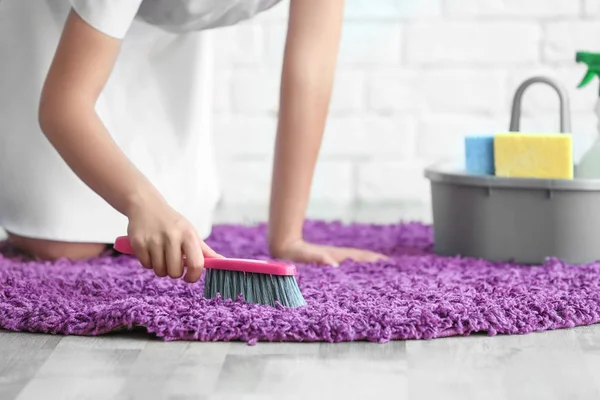 Woman cleaning small rug