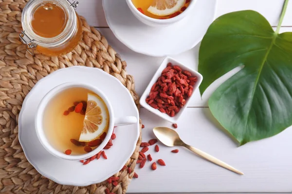 Cup with goji tea on wicker mat — Stock Photo, Image