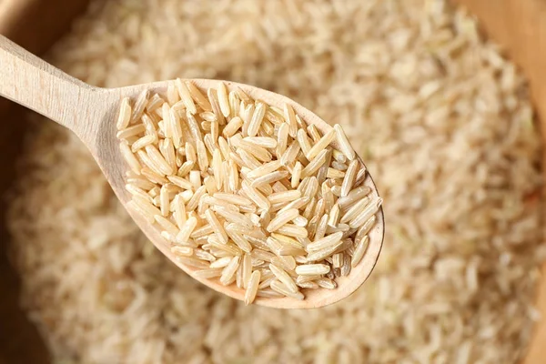 Wooden spoon with brown rice — Stock Photo, Image