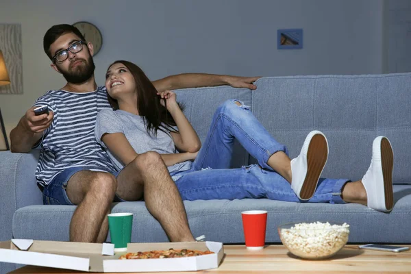 Jovem casal assistindo TV à noite em casa — Fotografia de Stock