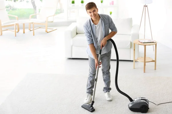 Hombre limpieza alfombra blanca con vacío en la sala de estar — Foto de Stock