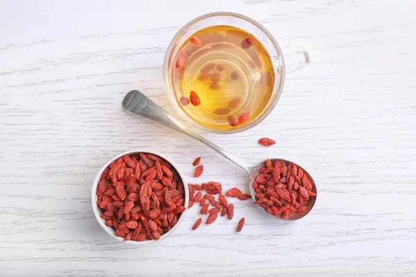 Composition with goji berries and tea on wooden background — Stock Photo, Image