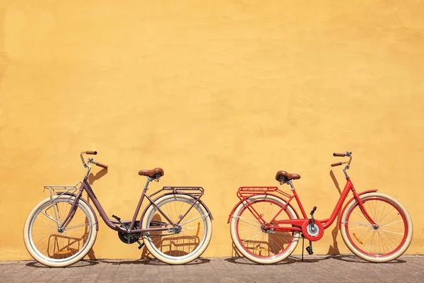 Dos nuevas bicicletas con estilo cerca de la pared de color al aire libre — Foto de Stock