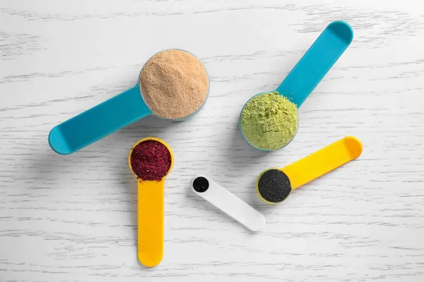 Composición con varios polvos de superalimentos coloridos y cucharas de medición — Foto de Stock