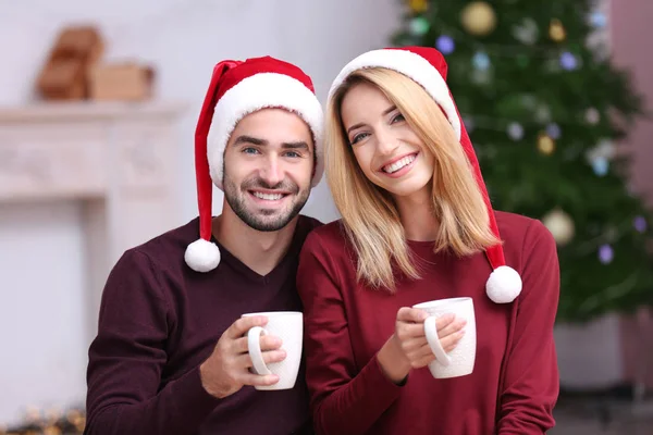 Feliz pareja joven bebiendo chocolate caliente en casa. Concepto de Navidad — Foto de Stock