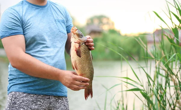 川の土手で獲れたて魚を持つ男 — ストック写真