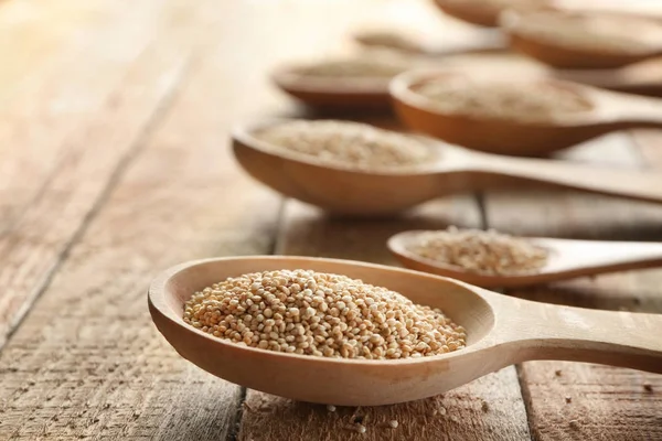 Lepels met quinoa zaden op houten tafel — Stockfoto