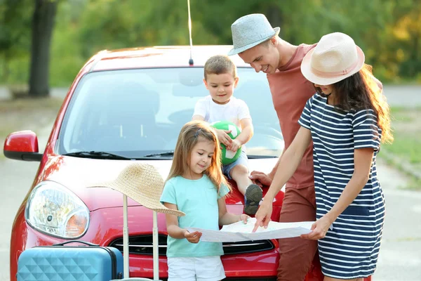 Happy family looking at map next to car in countryside — Stock Photo, Image