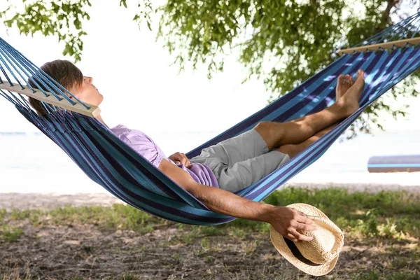 Mladý muž relaxuje v houpací síti venku — Stock fotografie