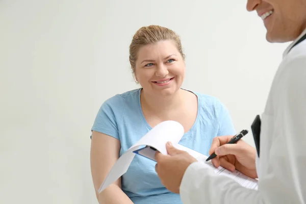 Женщина с избыточным весом обсуждает результаты анализов с врачом в больнице — стоковое фото
