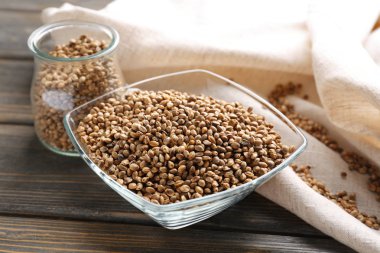 Cam ve ahşap masa üzerinde kenevir tohumu ile kase