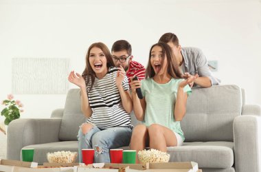 Arkadaşlar evde televizyon izliyor.