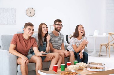 Arkadaşlar evde televizyon izliyor.