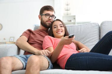 Evde televizyon izleyen genç bir çift.