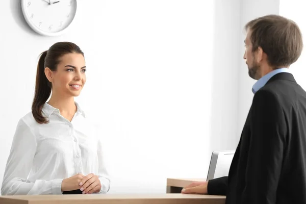 Jovem recepcionista atender cliente no escritório — Fotografia de Stock