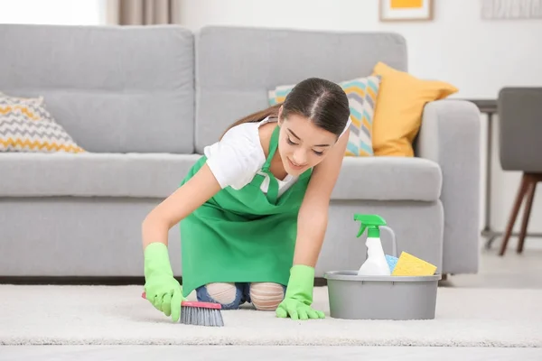 Frau putzt Teppich mit Bürste — Stockfoto