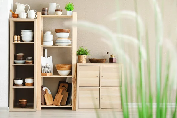 Soporte de almacenamiento con cerámica y utensilios de cocina de madera sobre fondo de pared claro —  Fotos de Stock