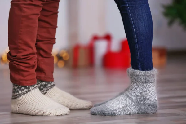 Beine eines jungen Paares in warmen Socken zu Hause. Weihnachtskonzept — Stockfoto