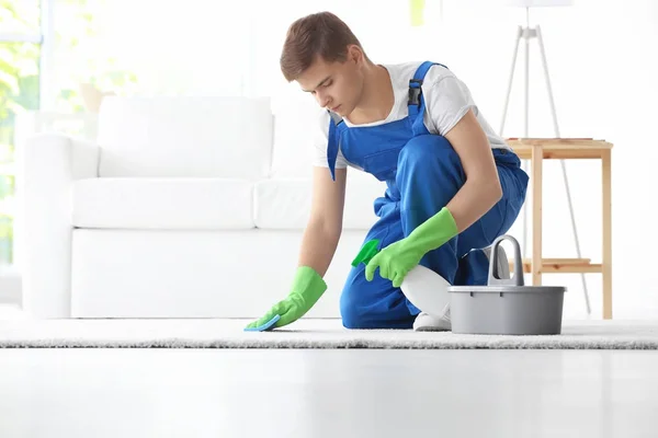 Hombre limpieza alfombra blanca en la sala de estar —  Fotos de Stock