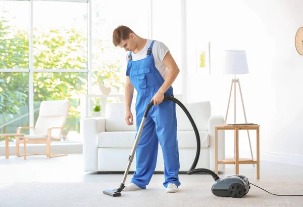 Man schoonmaak wit tapijt met vacuüm in woonkamer — Stockfoto