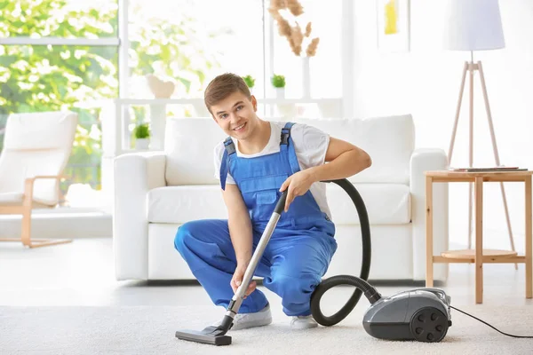 Mann reinigt weißen Teppich mit Staubsauger im Wohnzimmer — Stockfoto