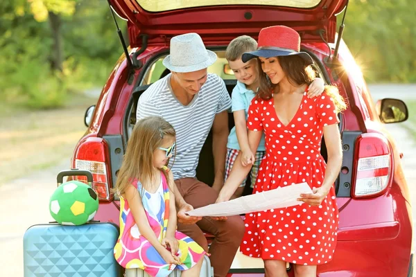 Happy family looking at map next to car in countryside — Stock Photo, Image