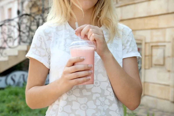 Mulher segurando copo de plástico de smoothie saboroso — Fotografia de Stock