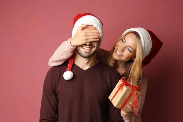 色の背景上の彼氏のクリスマス プレゼントを与える若い女性 — ストック写真