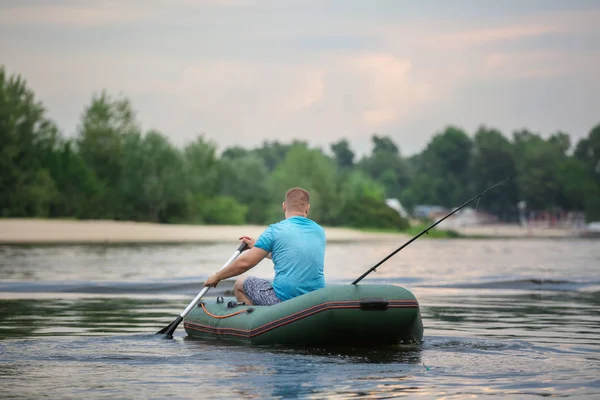 Homem que pesca do barco inflável no rio — Fotografia de Stock