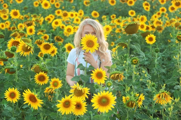 Junge Frau posiert mit Sonnenblume im Feld — Stockfoto