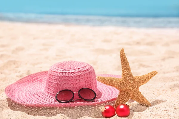 Chapéu com estrela do mar, decorações e óculos de sol na praia. Natal feriados conceito — Fotografia de Stock