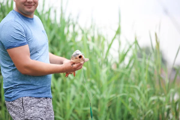 Hombre con peces recién capturados en la orilla del río — Foto de Stock