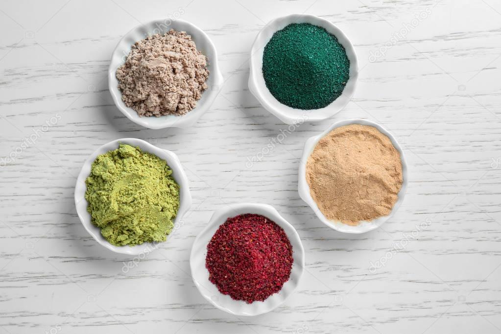 Various colorful superfood powders in white ceramic bowls
