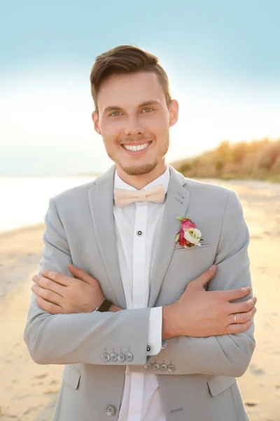 Knappe bruidegom in bruiloft pak op strand — Stockfoto