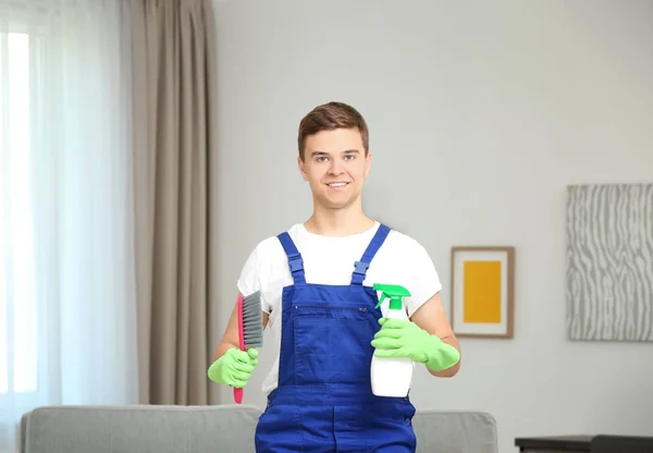 Mężczyzna trzyma pędzel i natrysku detergentu w salonie — Zdjęcie stockowe