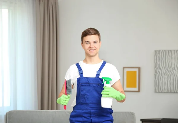 Man holding brush and detergent spray in living room — Stock Photo, Image