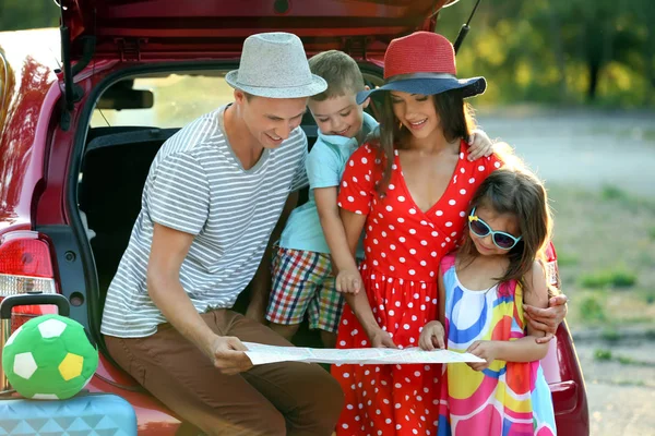 Happy family looking at map next to car in countryside