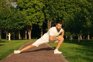 Sportif adam parkta güneşli günde germe