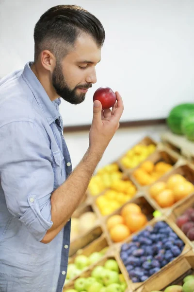 Joven con melocotón en el mercado — Foto de Stock